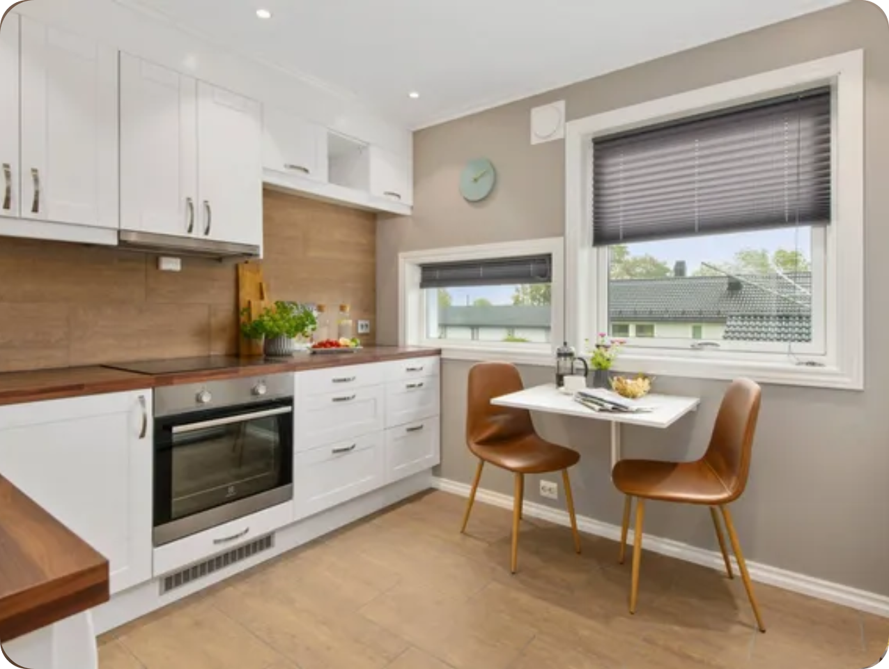 2222 A kitchen with white cabinets and brown chairs.